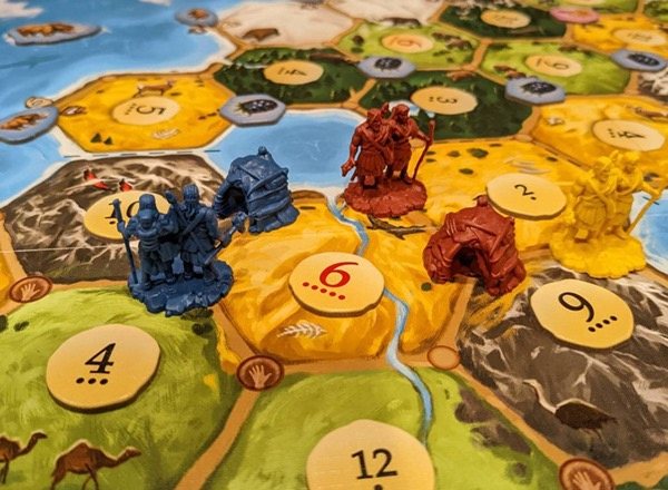 Player figures and huts on the Dawn of Humankind board